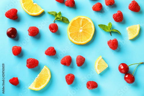 Fototapeta Naklejka Na Ścianę i Meble -  Composition with ripe aromatic raspberries, lemon slices and cherries on color background