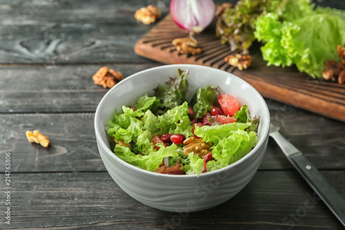 Bowl with delicious fresh salad on wooden table