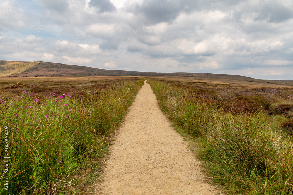 Looking down an empty pathway along the Pennine Way in Derbyshire, with a cloudy sky overhead Looking down an empty pathway along the Pennine Way in Derbyshire, with a cloudy sky overhead