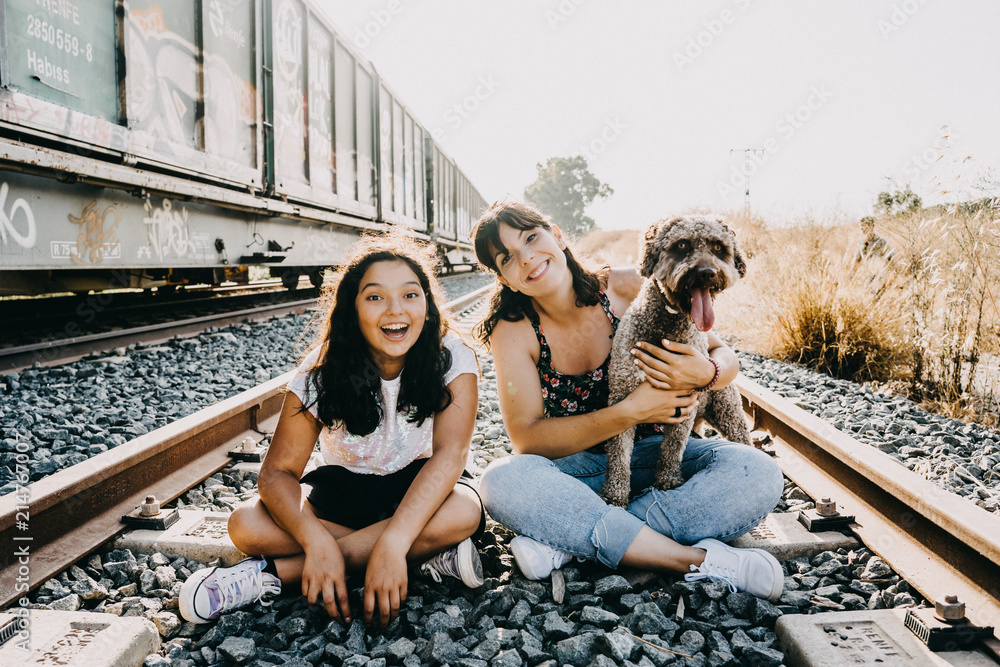 Fototapeta premium .Friends spending a fun summer afternoon at sunset, around abandoned train tracks in a relaxed and fun attitude with their dogs. Dog friendly. Lifestyle