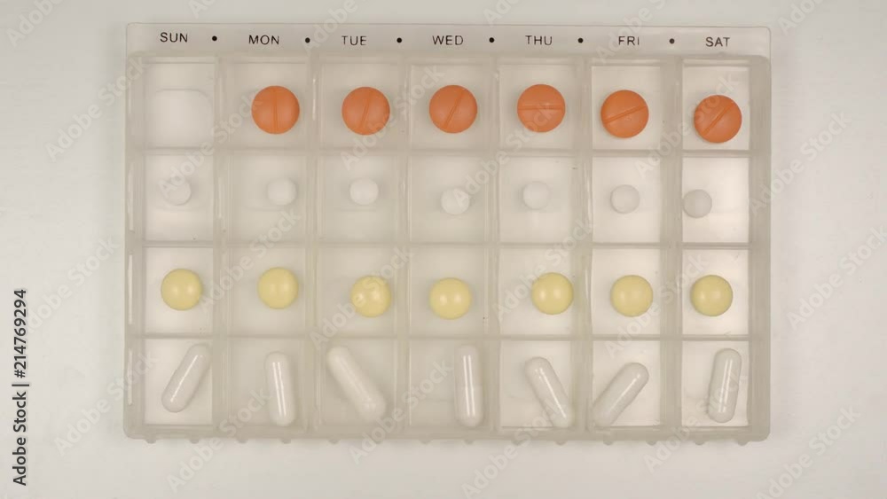 TOP VIEW: Female hand takes a pill from a pill organizer TOP VIEW: Female hand takes a pill from a pill organizer