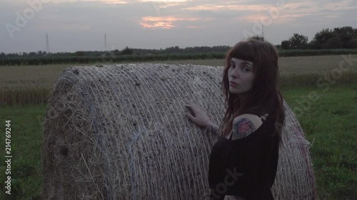 beautifull and alternative inked girl posing big bale of hay photo