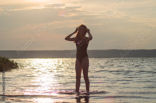 beautiful teen girl in swimsuit on sunset background dancing