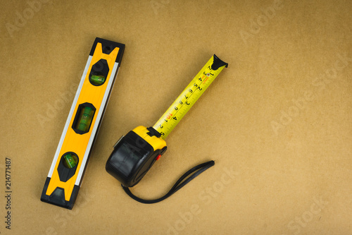 Measuring tape and Spirit level tool on brown background.
