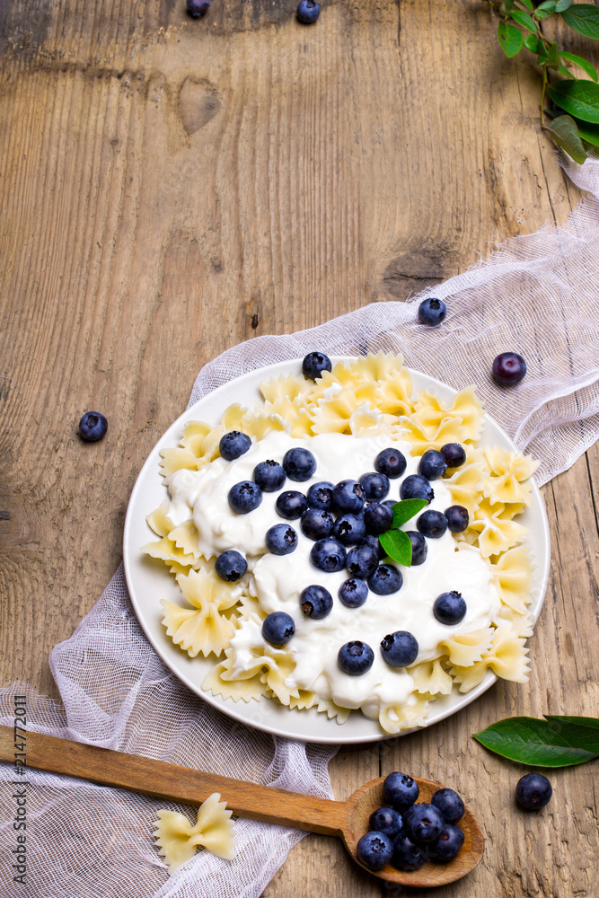 Tasty pasta with fresh organic blueberries and vanilla cream. Sweet dinner on retro wooden table. Tasty pasta with fresh organic blueberries and vanilla cream. Sweet dinner on retro wooden table.