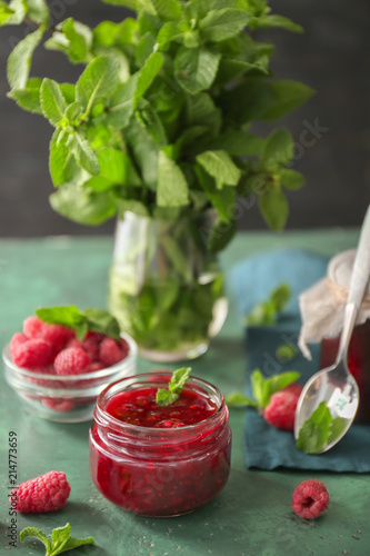 Glass jar with tasty raspberry jam on table