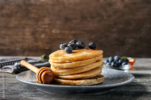 Plate with delicious pancakes and berries on wooden table