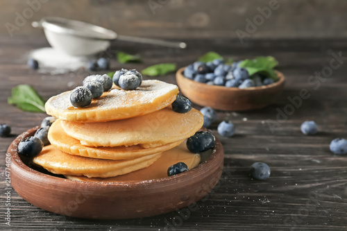 Bowl with delicious pancakes and berries on wooden table, closeup