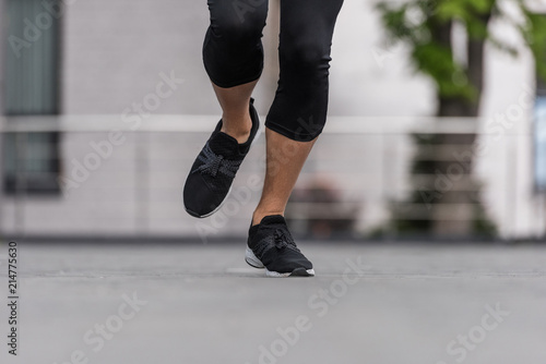 cropped image of female athlete in sneakers running at street