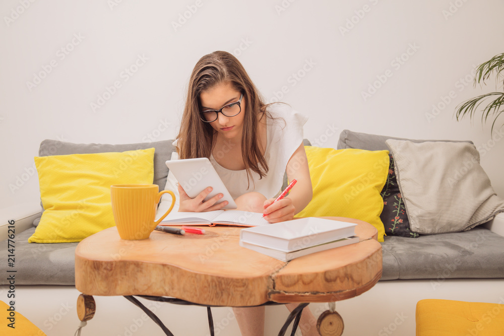 Cute teenager girl using digital tablet while sitting on the couch at home. Cute teenager girl using digital tablet while sitting on the couch at home.