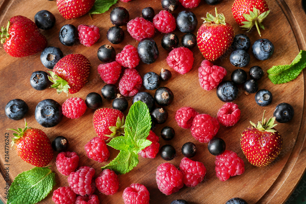 Obraz premium Delicious ripe berries on wooden board
