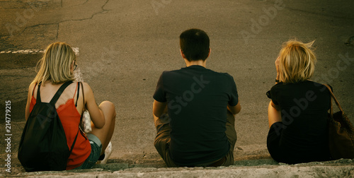 Tre ragazzi seduti sul marciapiede photo
