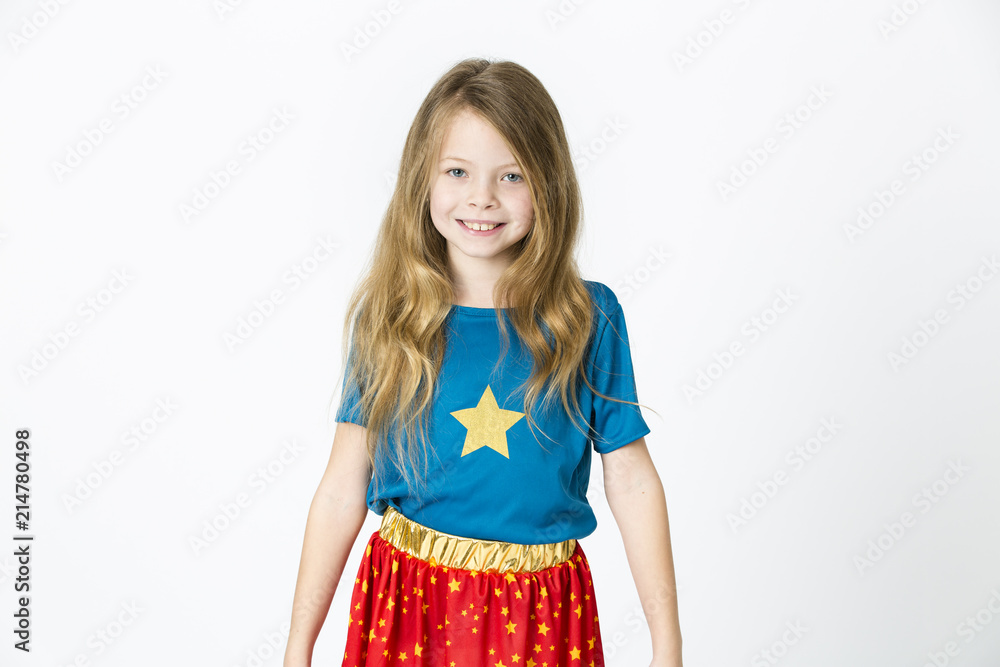 young, blond girl is dressed as a supergirl in the studio