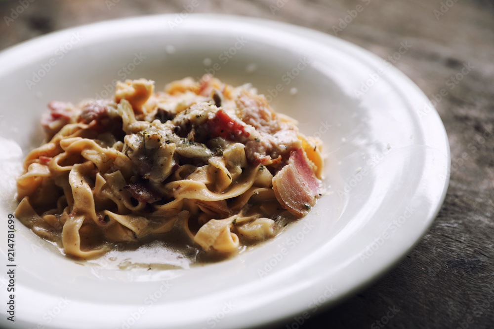 Pasta white sauce with bacon and mushroom on wood background in mystic light Pasta white sauce with bacon and mushroom on wood background in mystic light