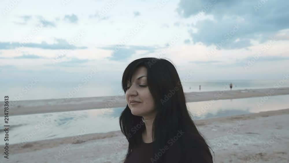Cute young woman walks along the beautiful sand beach at sunset. Slow motion. Cute young woman walks along the beautiful sand beach at sunset. Slow motion.