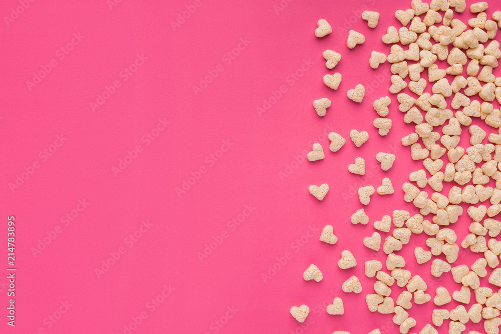 Top view of cereals in heart form on pink background