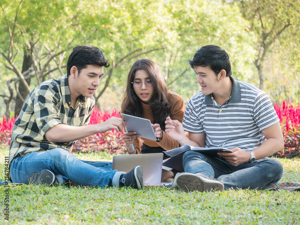 Group of college students with laptop and tablet computer while doing homework at park. Education concept. Group of college students with laptop and tablet computer while doing homework at park. Education concept.