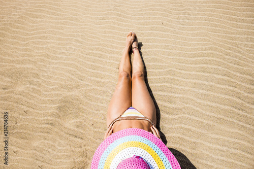 lady lay down on the beach with golden yellow sand relaxing and enjoy the summer holiday leisure activity. colored hat and beautiful middle age body. travel and destination concept. 