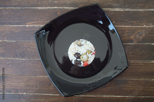 rice salad in a black plate on a wooden table seen from above