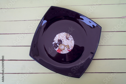 rice salad in a black plate on a green wooden table seen from above