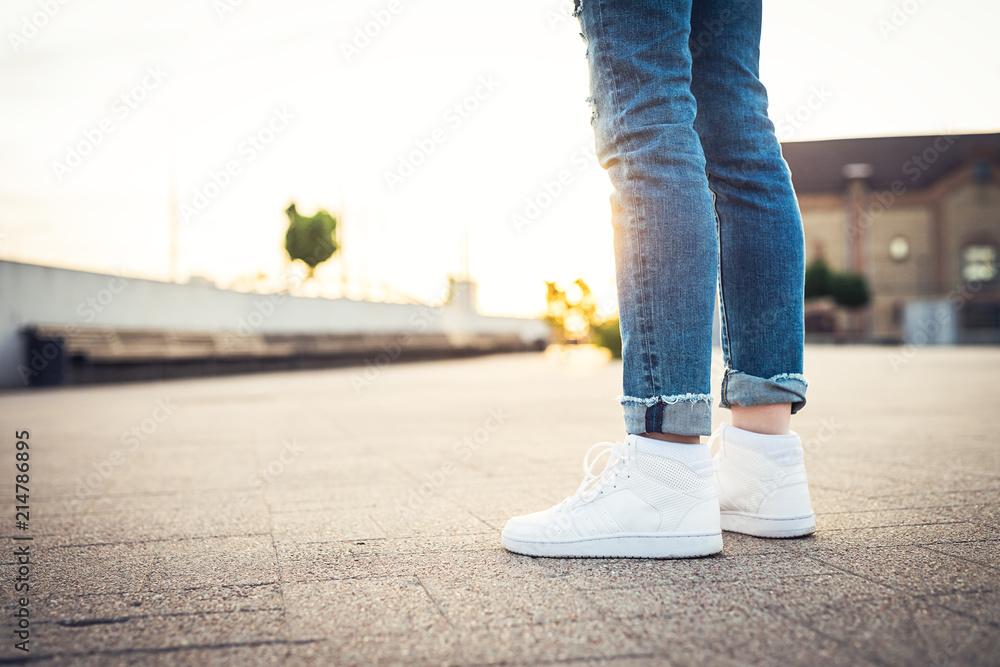High tops. Girl in blue jeans and white sport shoes standing on the ground  Stock-Foto | Adobe Stock