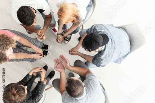 Top view on difficult youth talking with therapist while sitting in a circle during meeting