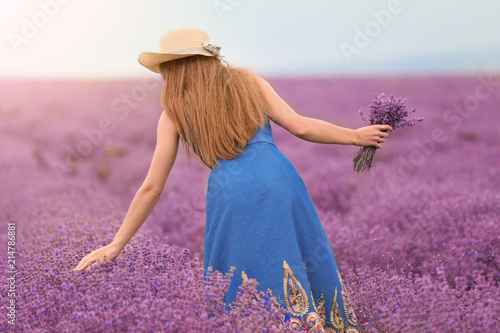 Beautiful young woman with bouquet of lavender in field on summer day