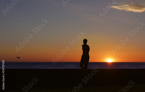 Silhouette of the running man on sunset sun. Man near the sea. Happy man. Silhouette of guy on sunset. Unknown man on sunset. Sunset. Summer holidays 