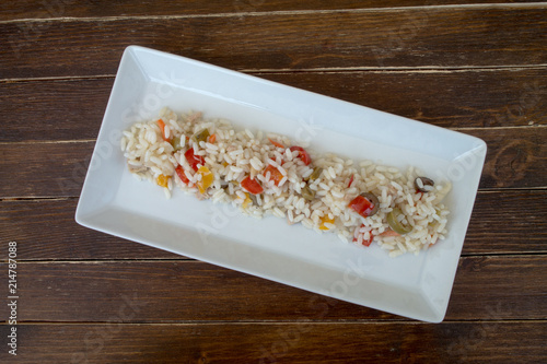 rice salad in a white tray on a wooden table seen from above