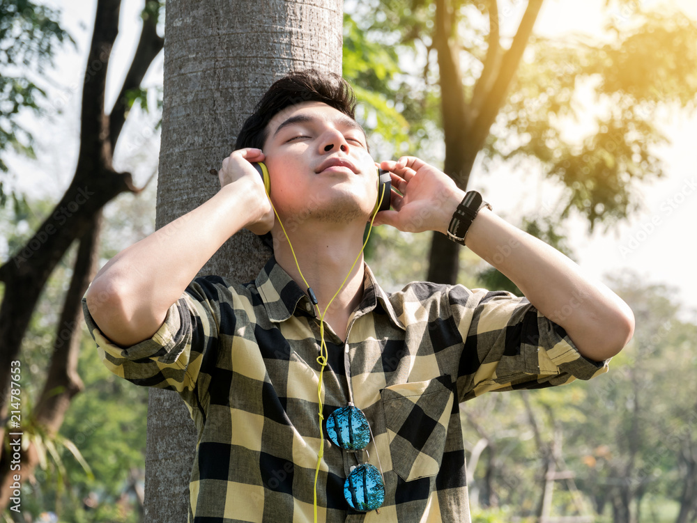Young handsome man listening music with headphones in the park.