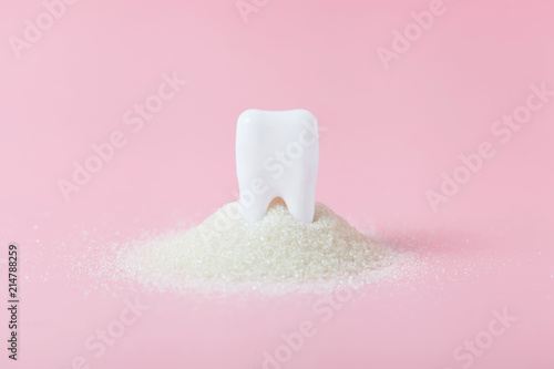 Plastic tooth in big pile of sugar. photo