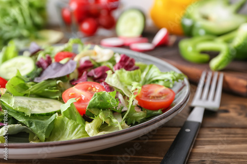 Plate with tasty vegetable salad on wooden table, closeup