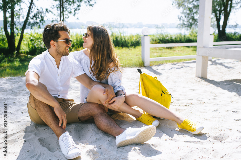 couple sitting on sandy city beach and looking at each other couple sitting on sandy city beach and looking at each other