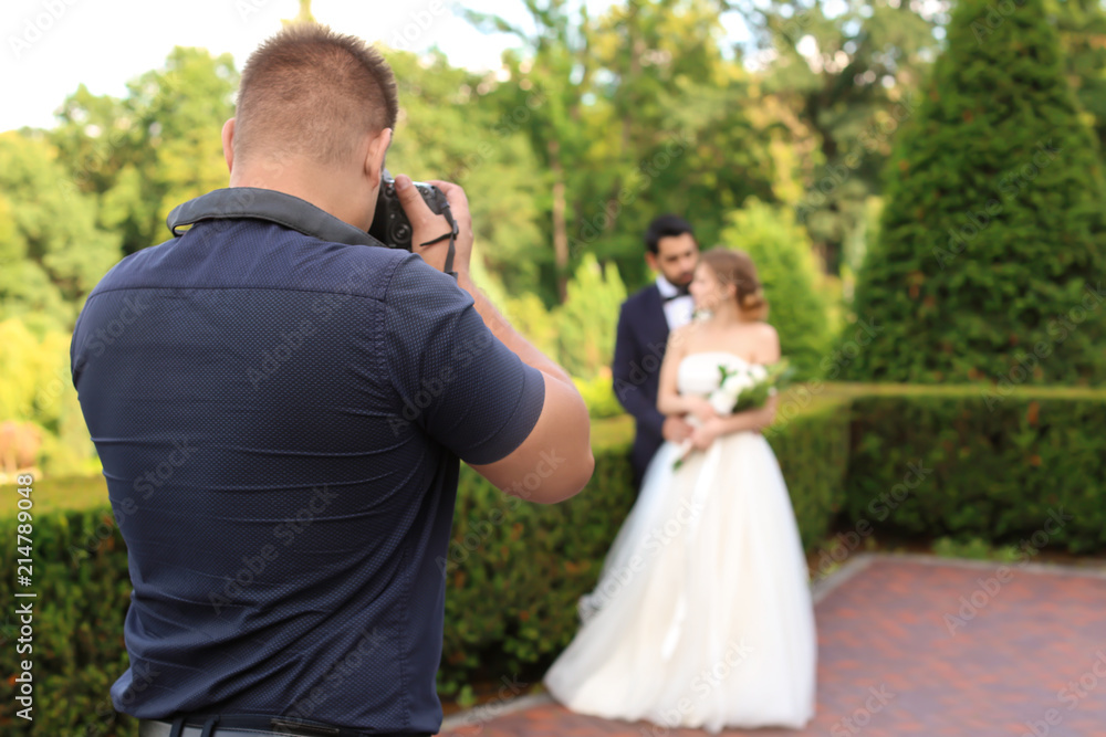 Professional photographer taking photo of wedding couple outdoors