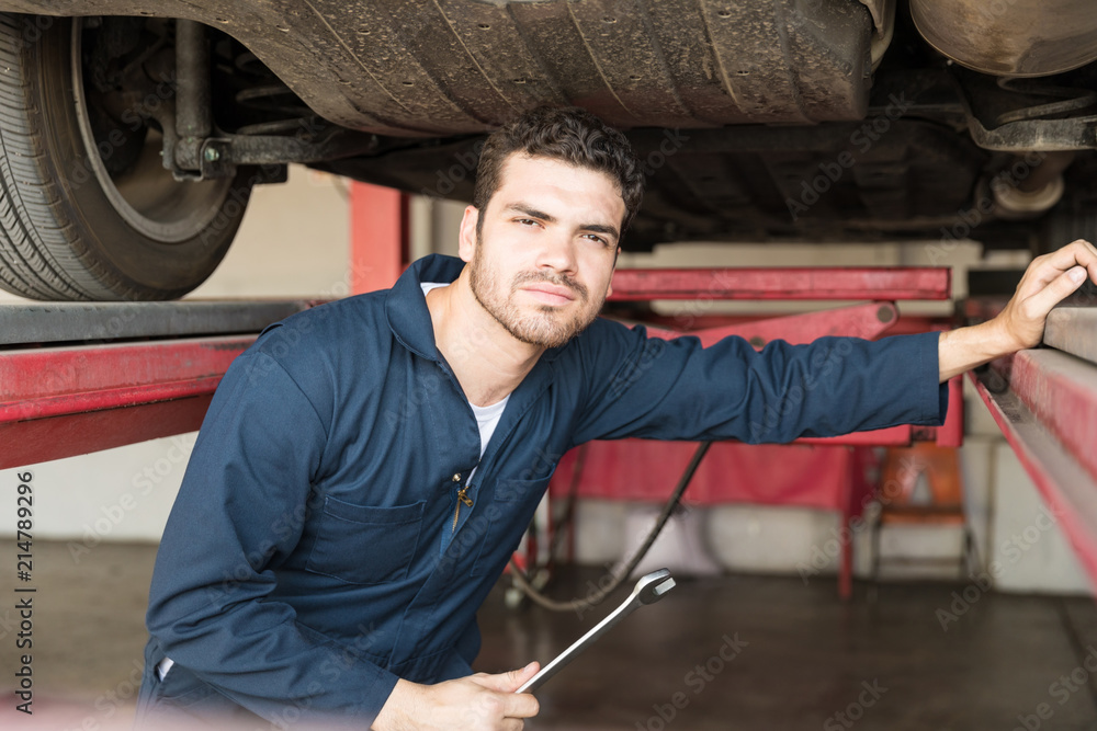 Handsome Mechanic Holding Spanner Under Car Handsome Mechanic Holding Spanner Under Car