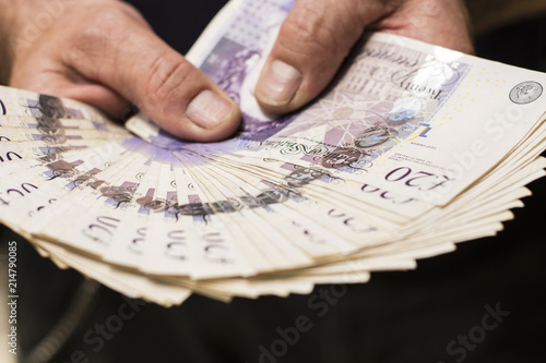 Holding twenty pound notes