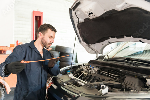 Engineer Checking Oil Level In Car Engine At Workshop