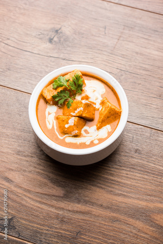 Paneer Butter Masala also known as Panir  makhani or makhanwala. served in a ceramic or terracotta bowl with fresh cream and coriander. Isolated over colourful moody background. selective focus