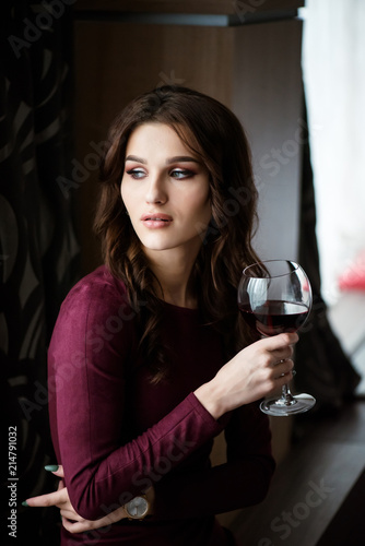 Elegant brunette lady with glass of red wine in restaurant.
