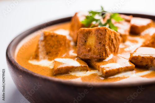 Paneer Butter Masala also known as Panir makhani or makhanwala. served in a ceramic or terracotta bowl with fresh cream and coriander. Isolated over colourful moody background. selective focus
