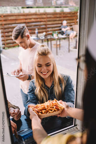 cropped image of chef giving french fries to customer in food truck