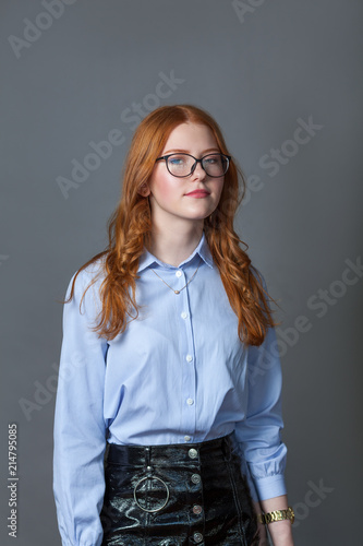 Portrait of happy nice schoolgirl teenager in blue shirt on gray background