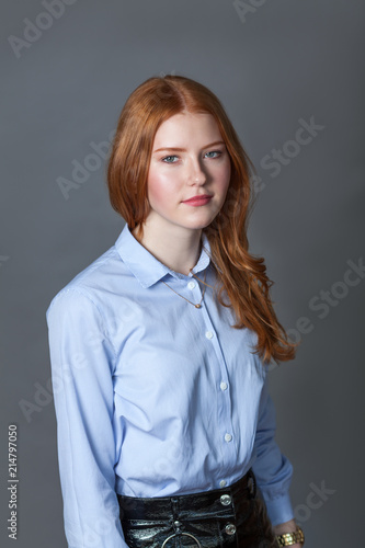 Portrait of happy nice schoolgirl teenager in blue shirt on gray background
