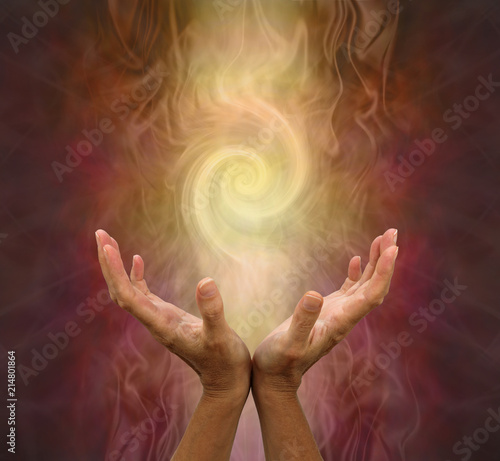 Channeling Golden Vortex healing energy  - female hands held open and palms upwards with a vortex energy formation above on a warm golden brown background
