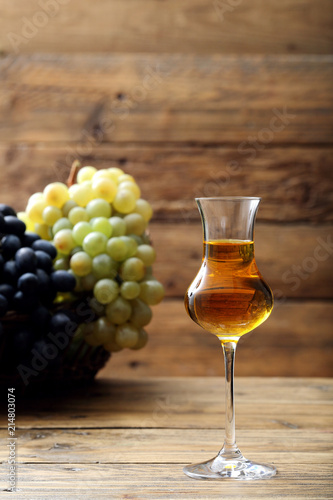 grappa disitllato di uva in bicchiere di vetro sfondo rustico