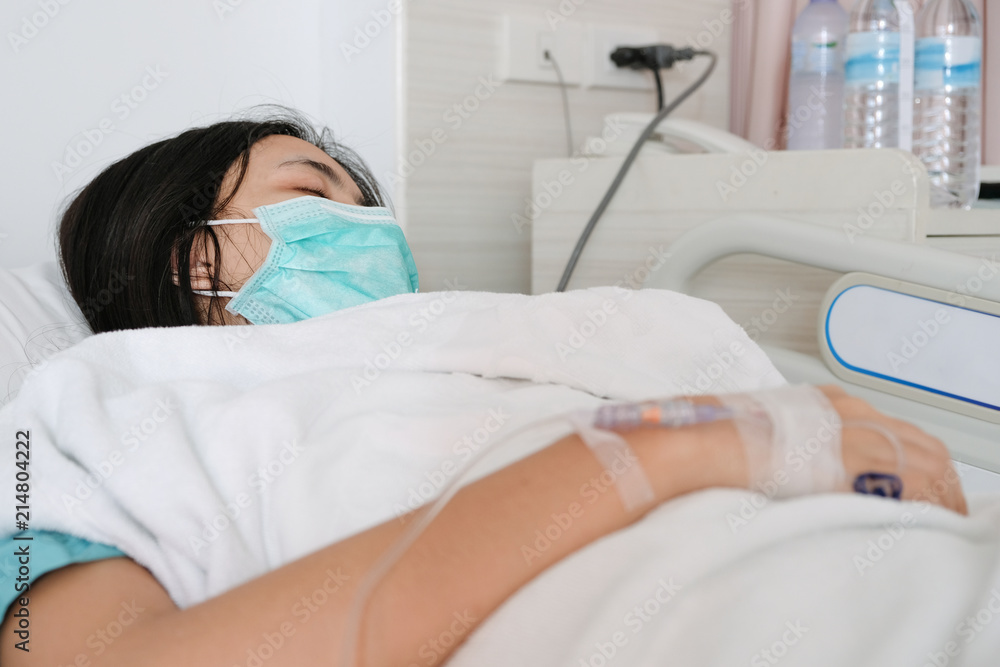 Close up young woman patient lay on bed in hospital with intravenous normal saline Close up young woman patient lay on bed in hospital with intravenous normal saline