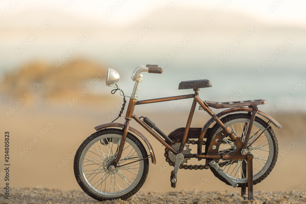 Fototapeta premium bicycle transport toy on sand sea beach in the evening sunset sky
