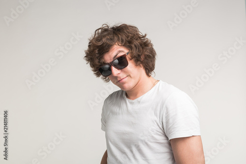 Portrait of cool guy in sunglasses in white t-shirt on white background © satura_