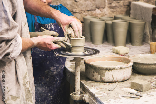 Potter teaches to sculpt in clay pot on a turning pottery wheel photo