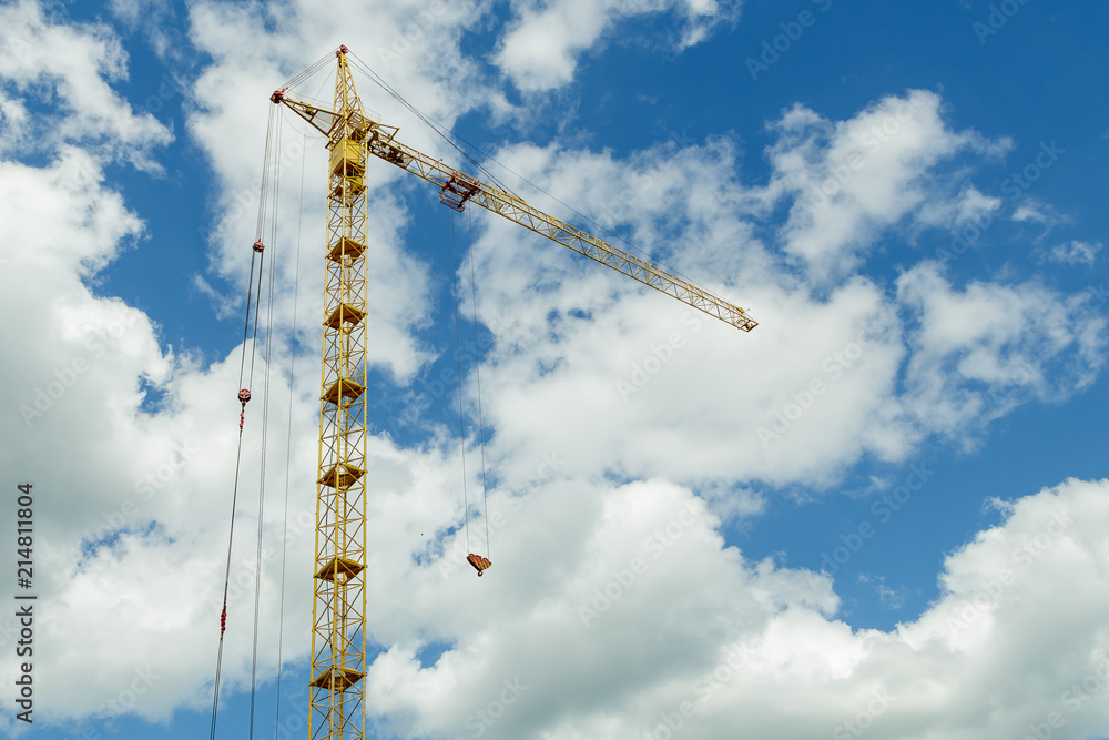 building tower crane. Against the blue sky with moving white clouds. Time laps